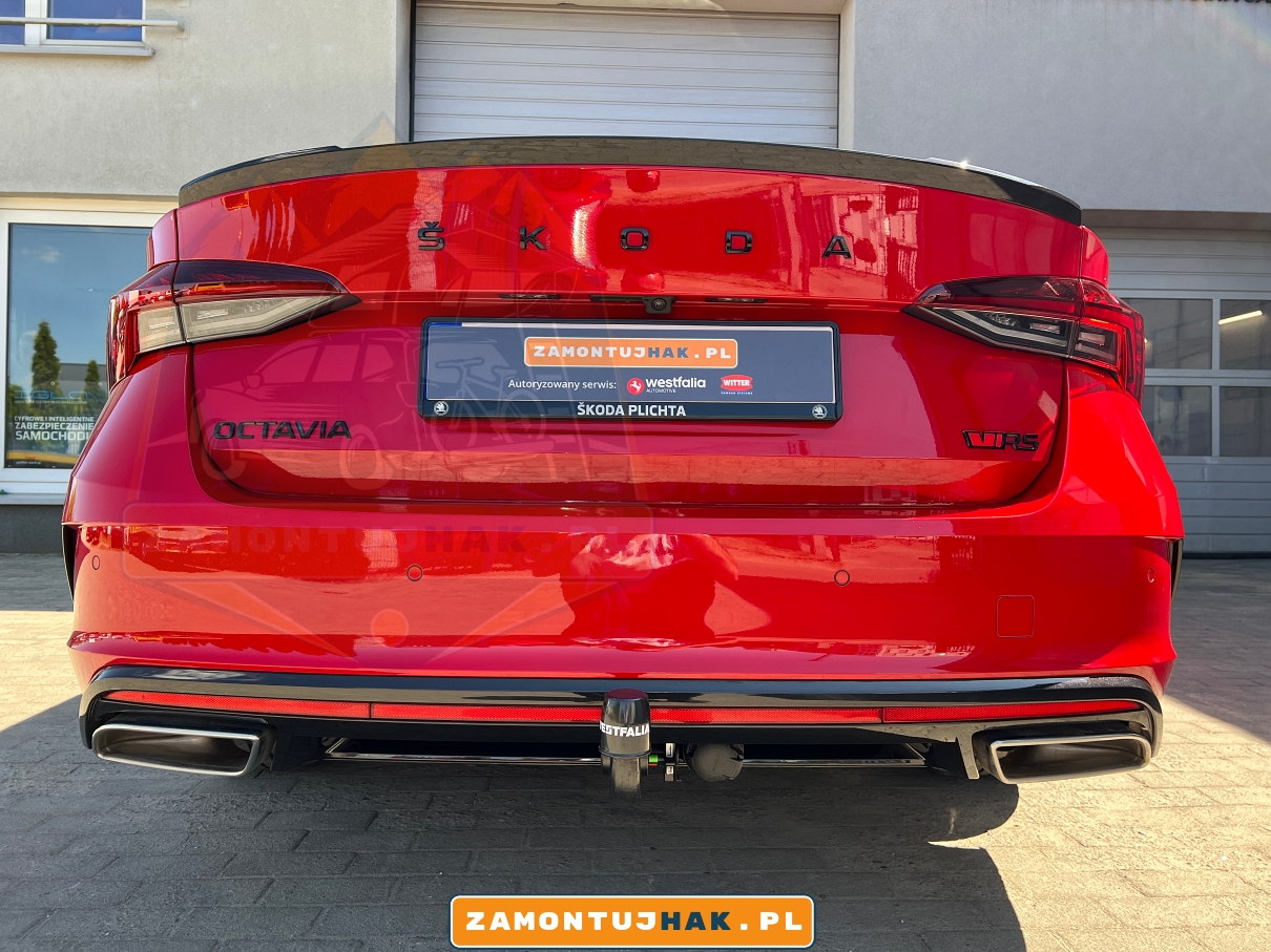 Czerwona Skoda Octavia IV RS zaparkowana przed warsztatem z zamontowanym hakiem holowniczym na tylnym zderzaku